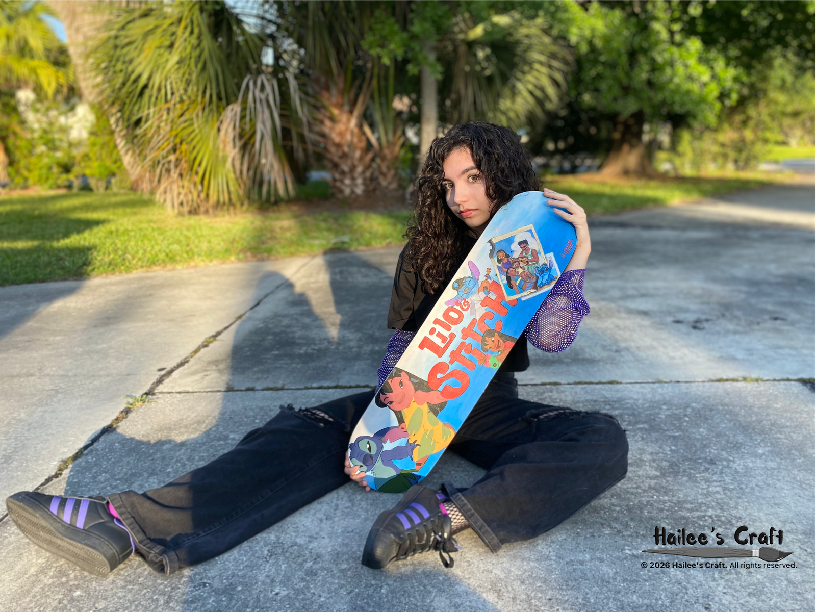 a blue and white skate board base plate painted with disneys lilo and stitch charecters. the movies tittle is painted in red in the center of the board